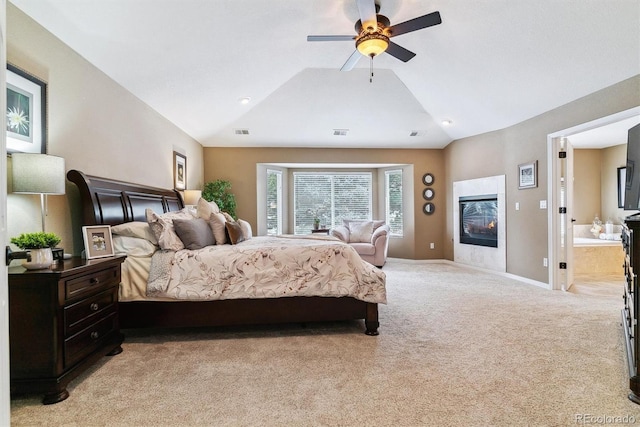 carpeted bedroom with ceiling fan, a fireplace, ensuite bathroom, and vaulted ceiling