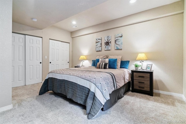 bedroom with multiple closets and light colored carpet