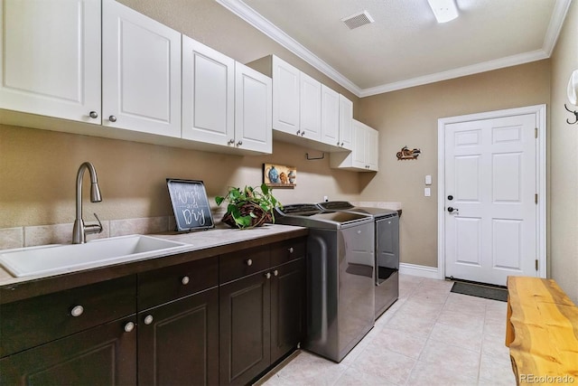 laundry room featuring crown molding, sink, washer and clothes dryer, cabinets, and light tile patterned flooring