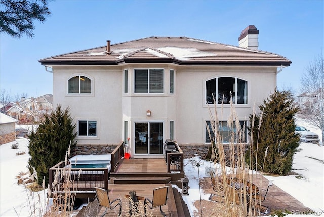 snow covered back of property with a wooden deck