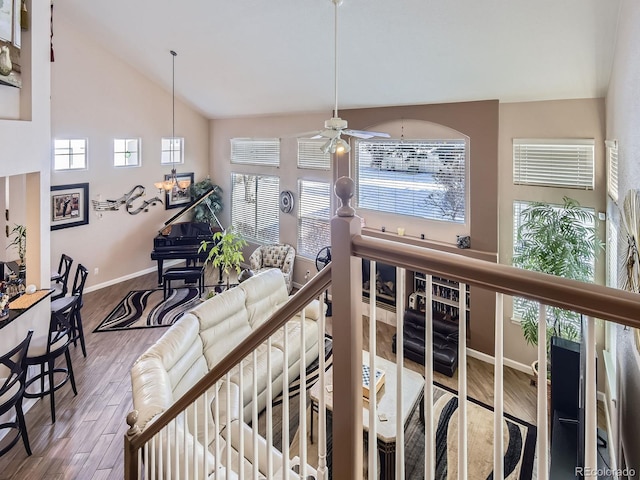 interior space with high vaulted ceiling, baseboards, wood finished floors, and an upstairs landing