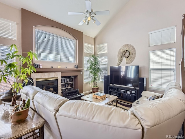 living room with high vaulted ceiling, a ceiling fan, a wealth of natural light, and a tile fireplace