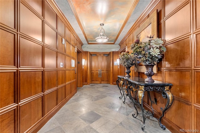 hallway with a raised ceiling, crown molding, and wooden walls