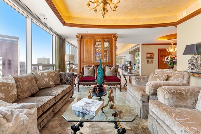 living room with a raised ceiling, ornamental molding, and a chandelier