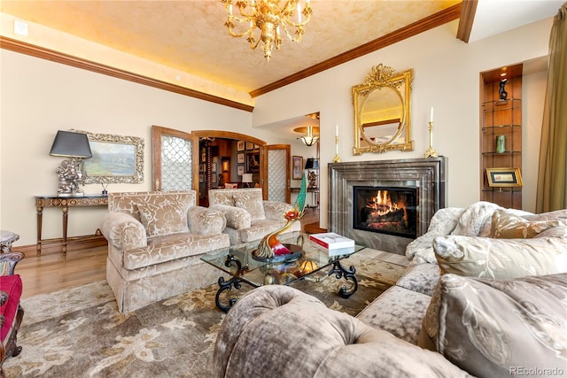 living room featuring hardwood / wood-style floors, crown molding, an inviting chandelier, and a fireplace