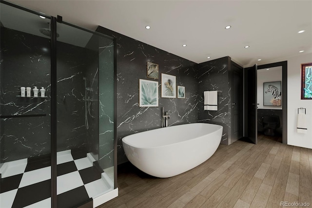 bathroom with wood-type flooring, a tub to relax in, and tile walls