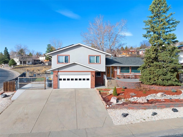 split level home featuring a gate, fence, driveway, an attached garage, and brick siding