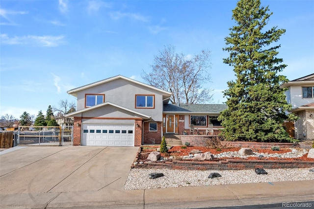 split level home with brick siding, an attached garage, fence, stucco siding, and driveway