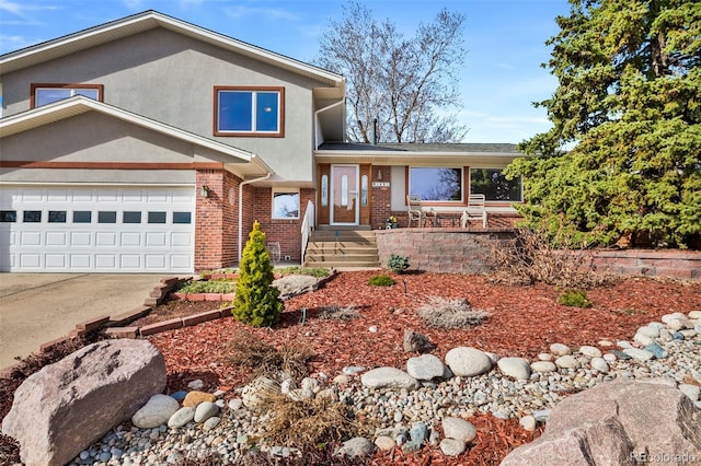 split level home with brick siding, stucco siding, and driveway