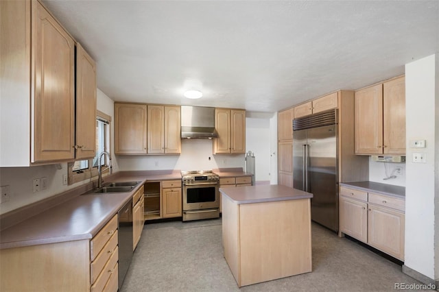 kitchen with a center island, light brown cabinetry, stainless steel appliances, wall chimney exhaust hood, and a sink