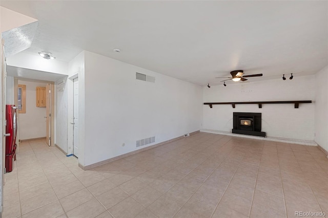 unfurnished living room with light tile patterned floors, visible vents, a ceiling fan, and a glass covered fireplace