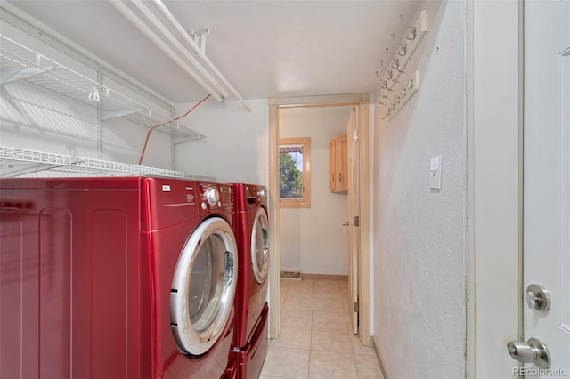 clothes washing area featuring laundry area, light tile patterned flooring, washing machine and dryer, and baseboards