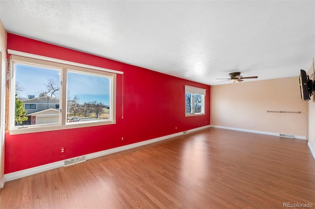 empty room featuring visible vents, baseboards, and wood finished floors