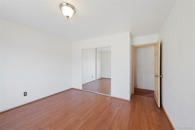 unfurnished bedroom with a closet, baseboards, and wood finished floors