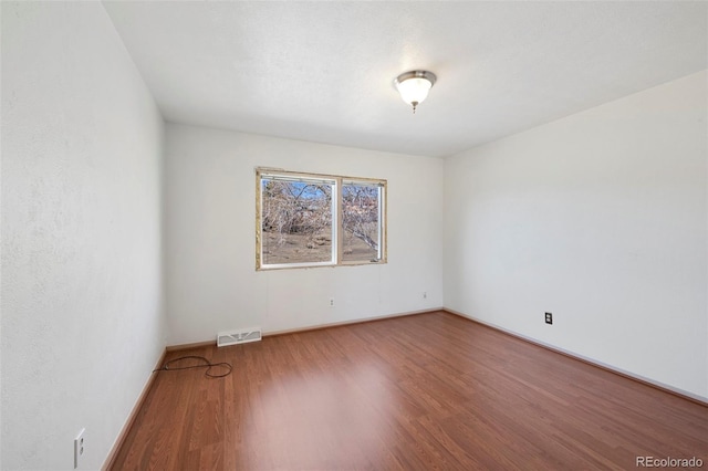 empty room with visible vents, baseboards, and wood finished floors