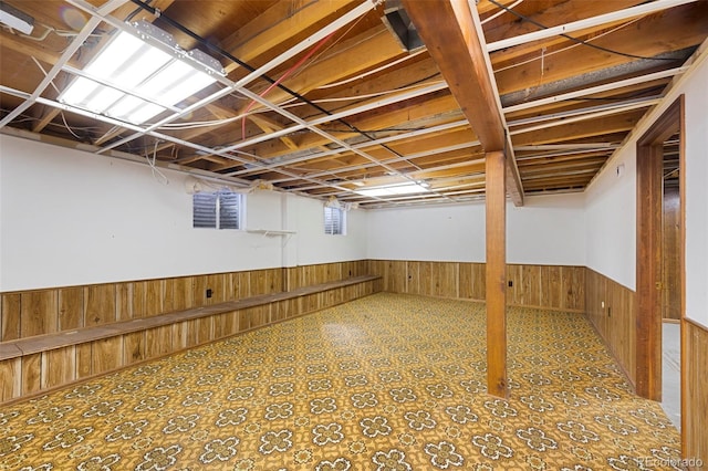 below grade area featuring tile patterned floors, wood walls, and wainscoting