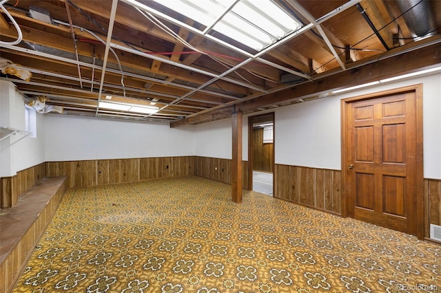 finished basement featuring tile patterned floors, visible vents, a wainscoted wall, and wood walls