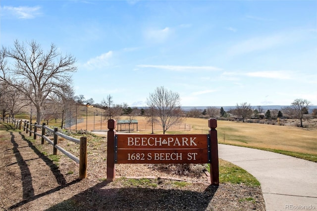 view of property's community with a rural view, a lawn, and fence