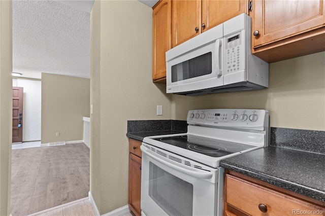3720 S Fairplay Way, Aurora, CO 80014 - kitchen with white appliances, dark countertops, brown cabinets, and light wood-style floors