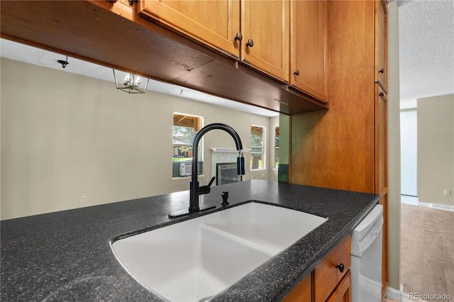 3720 S Fairplay Way, Aurora, CO 80014 - kitchen with a sink, white dishwasher, brown cabinets, and a tile fireplace