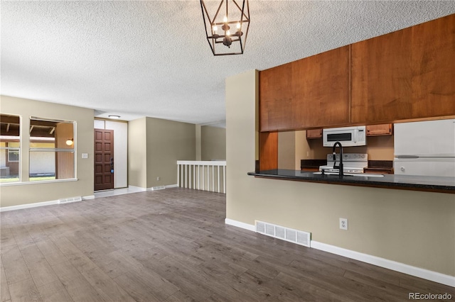 3720 S Fairplay Way, Aurora, CO 80014 - kitchen featuring white appliances, dark wood finished floors, a textured ceiling, brown cabinets, and dark countertops