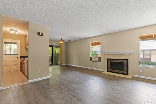 3720 S Fairplay Way, Aurora, CO 80014 - unfurnished living room featuring a tile fireplace, wood finished floors, a textured ceiling, a chandelier, and cooling unit