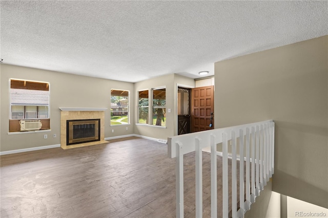 3720 S Fairplay Way, Aurora, CO 80014 - unfurnished living room with hardwood / wood-style floors, a textured ceiling, baseboards, cooling unit, and a tiled fireplace