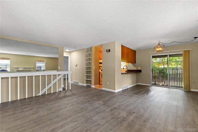 3720 S Fairplay Way, Aurora, CO 80014 - unfurnished living room featuring a textured ceiling, wood finished floors, baseboards, and a chandelier