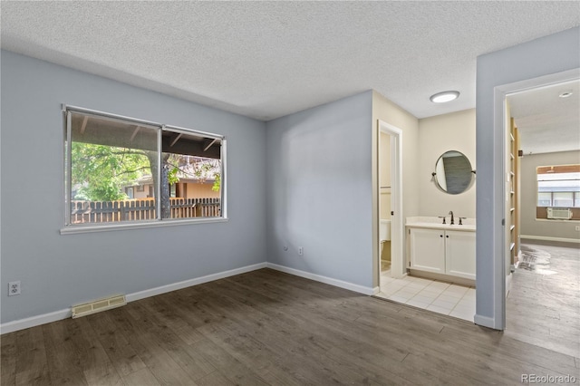 3720 S Fairplay Way, Aurora, CO 80014 - empty room featuring wood finished floors, a sink, a textured ceiling, cooling unit, and baseboards