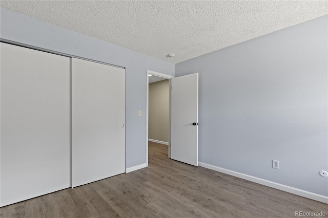 3720 S Fairplay Way, Aurora, CO 80014 - unfurnished bedroom with wood finished floors, baseboards, a closet, and a textured ceiling