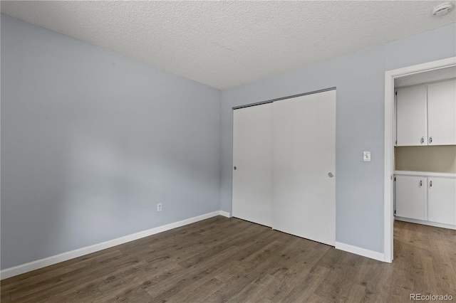 3720 S Fairplay Way, Aurora, CO 80014 - unfurnished bedroom featuring wood finished floors, a closet, baseboards, and a textured ceiling