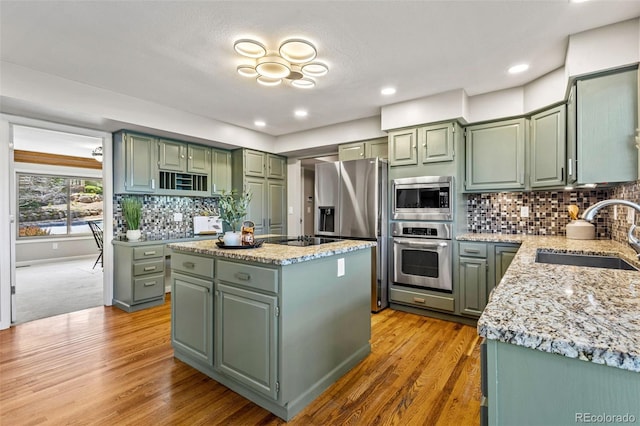 kitchen featuring light stone countertops, sink, stainless steel appliances, a kitchen island, and green cabinetry