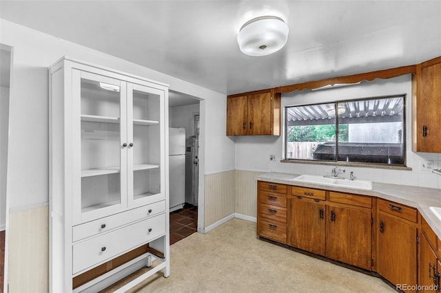 7760 Magnolia St, Commerce City, CO 80022 - kitchen with a sink, freestanding refrigerator, brown cabinets, light countertops, and wainscoting