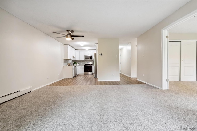 unfurnished living room featuring ceiling fan, a baseboard radiator, and light carpet