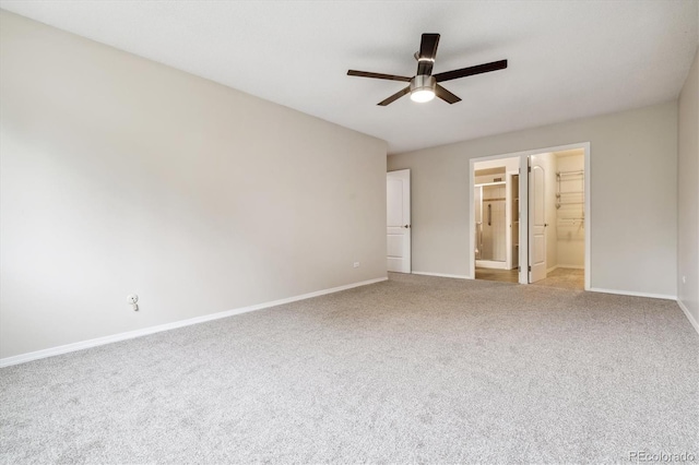 unfurnished bedroom with ceiling fan, light carpet, connected bathroom, and a walk in closet