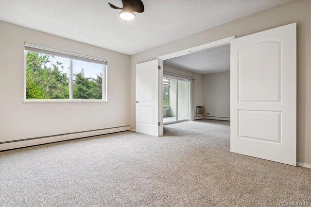 carpeted spare room featuring a textured ceiling and a baseboard heating unit