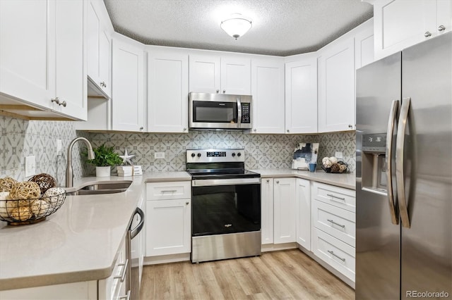 kitchen with appliances with stainless steel finishes, white cabinetry, and sink