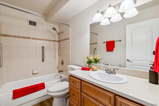 full bathroom featuring tiled shower / bath combo, vanity, and toilet