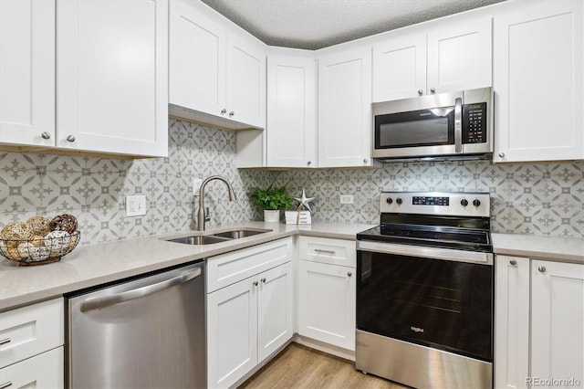 kitchen with light countertops, white cabinets, appliances with stainless steel finishes, and a sink