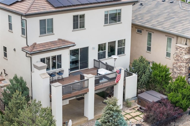 10468 Ladera Dr, Lone Tree, CO 80124 - back of property with a hot tub, a deck, solar panels, and stucco siding