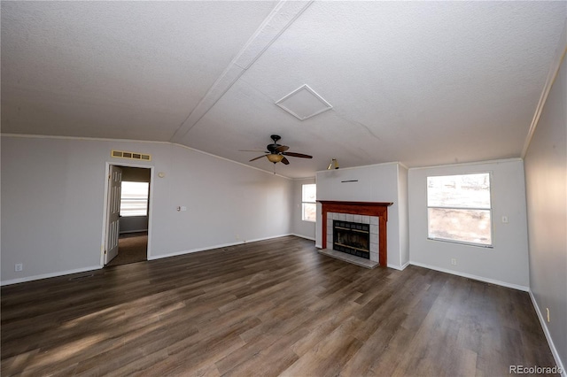 unfurnished living room with ceiling fan, dark hardwood / wood-style floors, a tile fireplace, and plenty of natural light