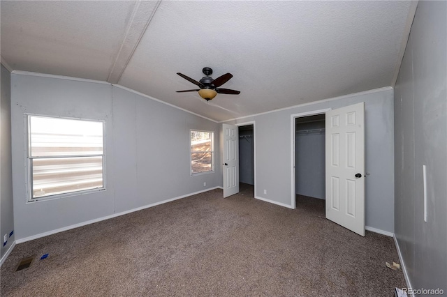 unfurnished bedroom featuring lofted ceiling, dark colored carpet, two closets, a textured ceiling, and ceiling fan