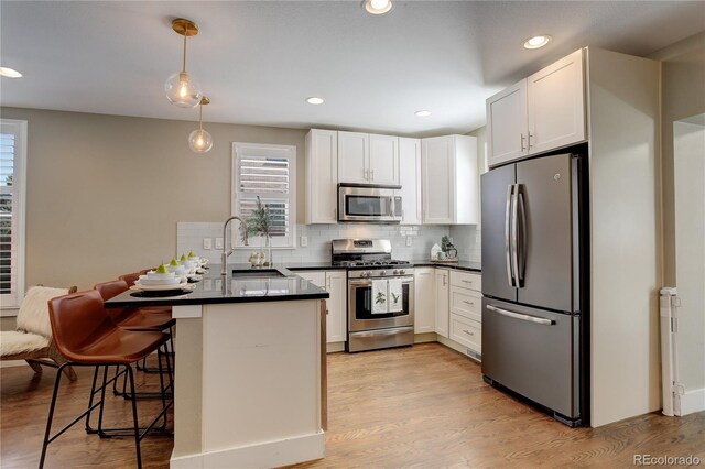 kitchen with a kitchen breakfast bar, stainless steel appliances, white cabinetry, and kitchen peninsula