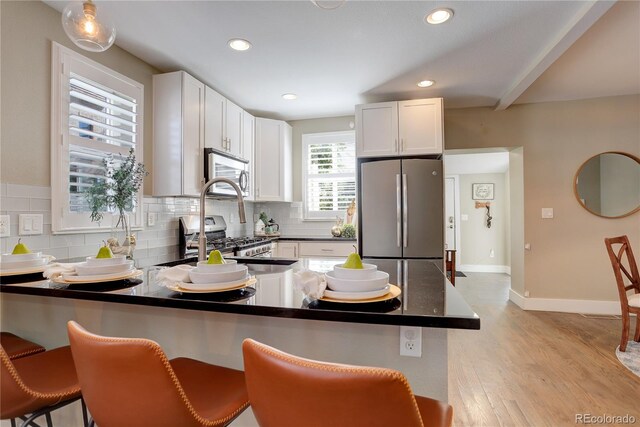 kitchen featuring light hardwood / wood-style floors, white cabinetry, stainless steel appliances, and a breakfast bar