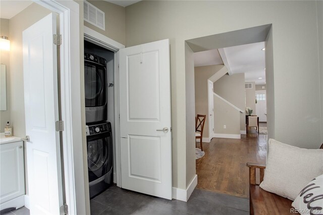 laundry room featuring stacked washing maching and dryer and dark hardwood / wood-style flooring