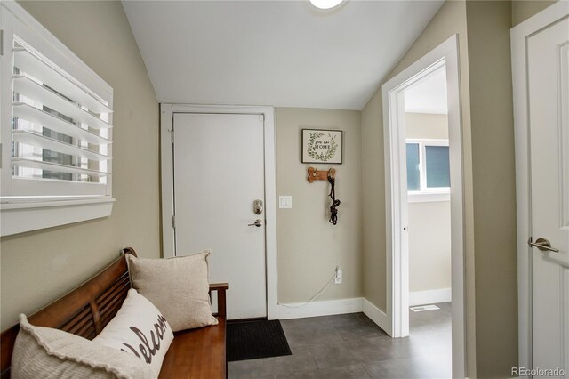 foyer featuring dark tile patterned flooring and lofted ceiling