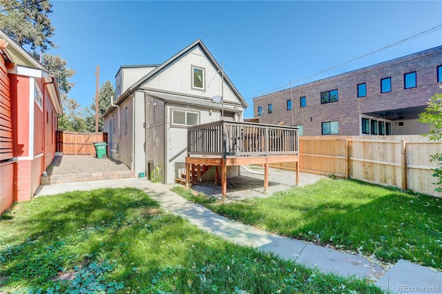 rear view of house featuring a wooden deck and a lawn