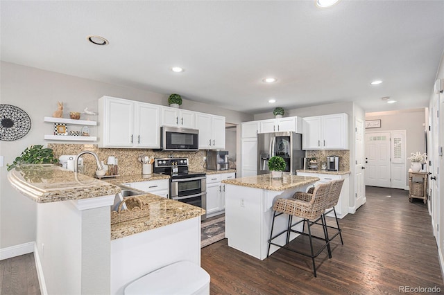 13340 Saint Paul St, Thornton, CO 80241 - kitchen with stainless steel appliances, open shelves, a kitchen bar, white cabinetry, and decorative backsplash