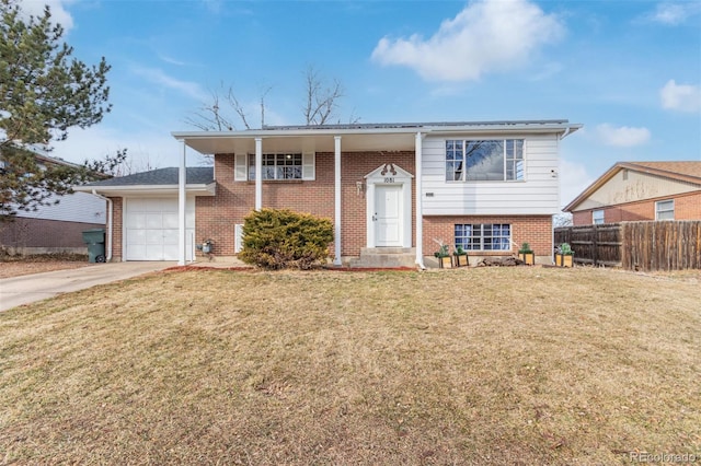 split foyer home featuring a garage, concrete driveway, fence, a front lawn, and brick siding