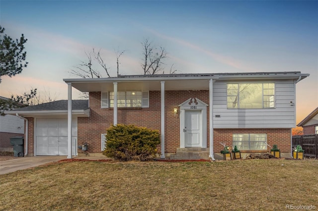 split foyer home with an attached garage, brick siding, fence, concrete driveway, and a front yard